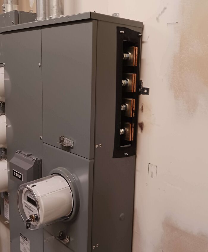 Dangerous electrical panel with exposed components on a wall.