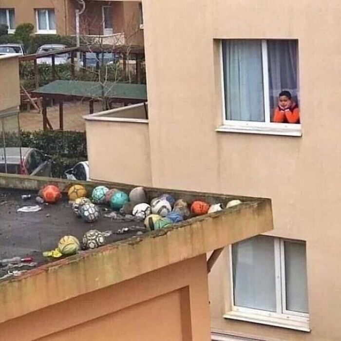Child gazes out window at random cursed image of balls covering a rooftop.