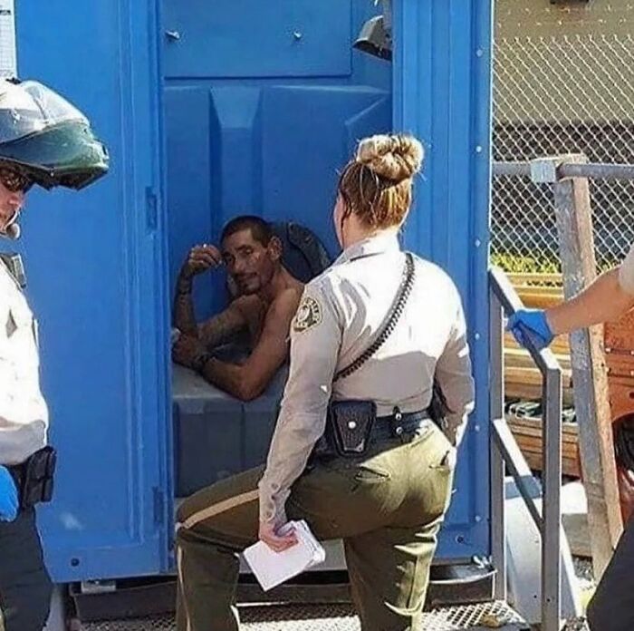 Two officers outside a portable toilet, with a man inside, exemplifying a random cursed image scenario.
