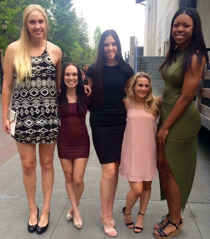 A group of five women posing together, creating an unusual height illusion, making the photo look fake but it's real.