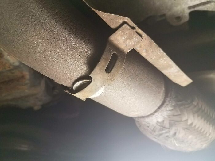 Failed repair attempt on a metal pipe with a poorly attached clamp.