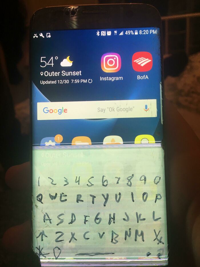 Broken phone screen with handwritten keyboard repair attempt.