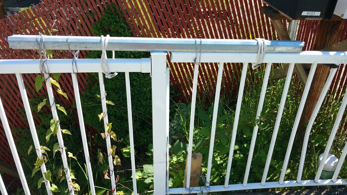 Failed repair attempt on a metal fence using wires, highlighting a DIY mishap in an outdoor setting.