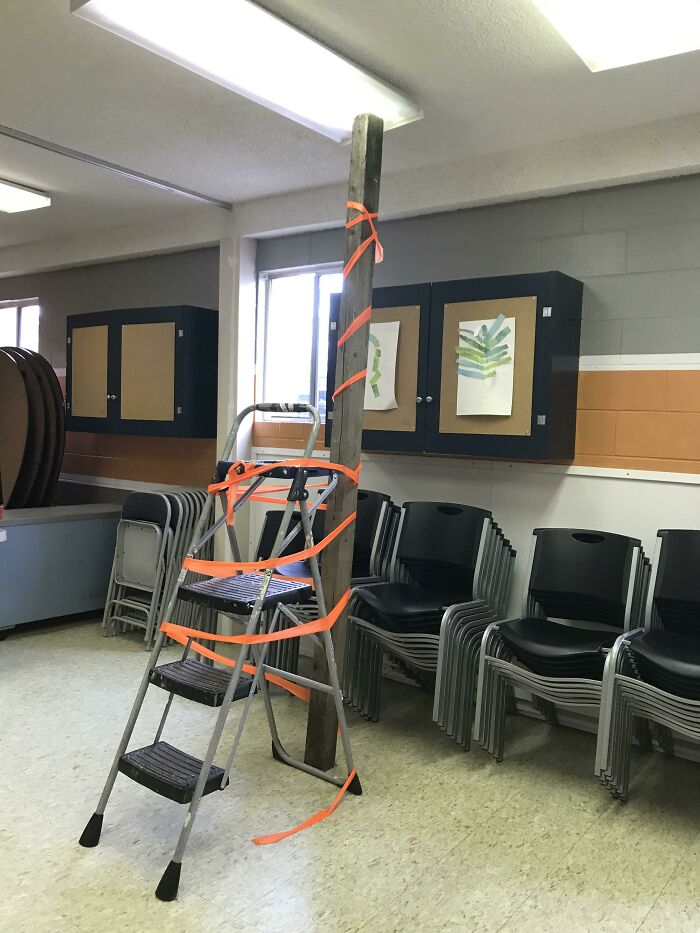 A failed repair attempt with a ladder and wooden pole awkwardly tied together using orange straps.