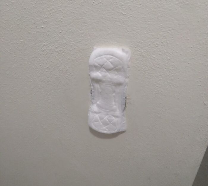 Failed repair attempt using a sanitary pad on a wall, highlighting a humorous and ineffective fix.