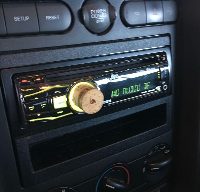 Car stereo with a cork as a volume k**b, showcasing a failed repair attempt.