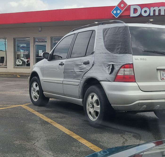 SUV with duct tape repair parked outside a Domino's store.