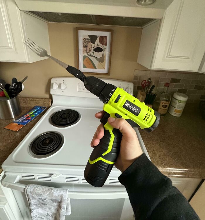 Failed repair attempt with a drill holding a fork instead of a drill bit, in a kitchen setting.