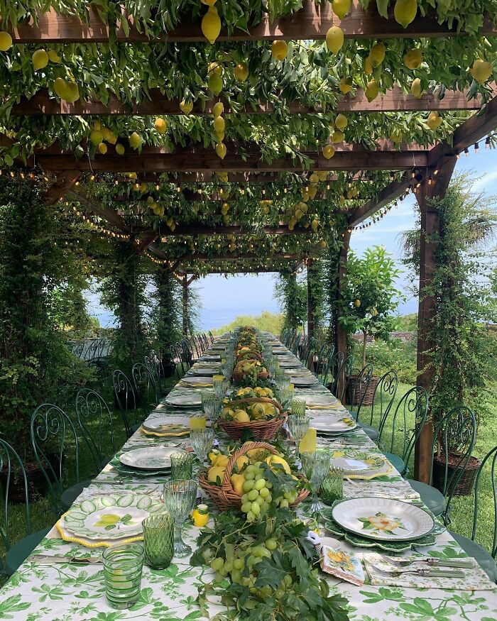 Beautiful outdoor dining setup under a pergola adorned with hanging lemons.