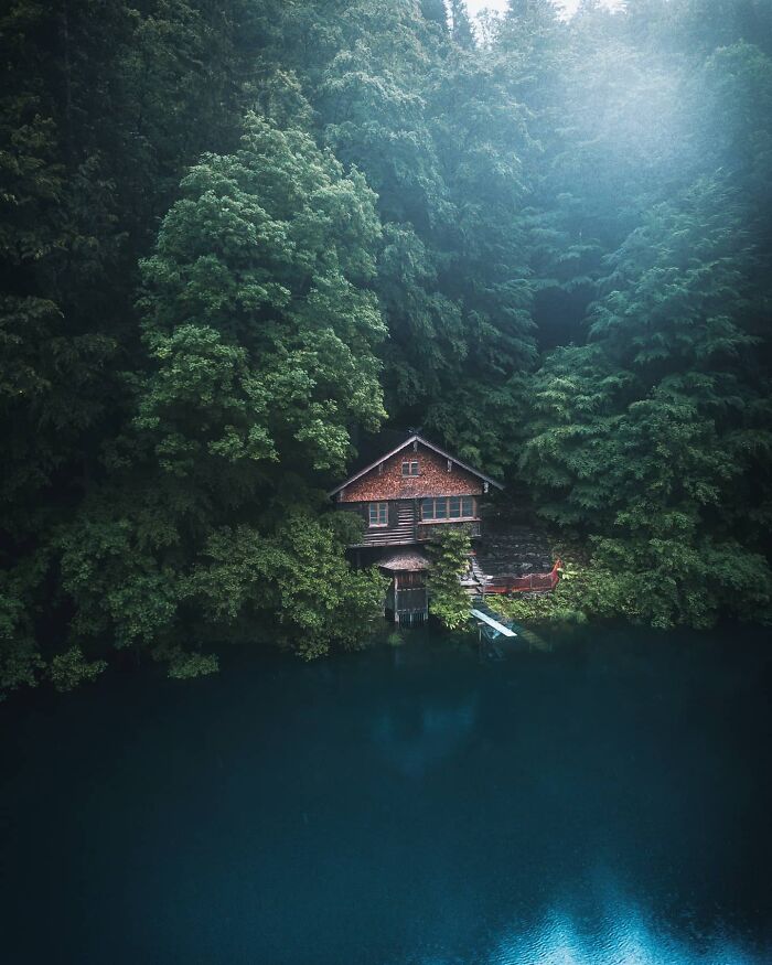 Cabin nestled among lush trees by a tranquil blue lake, highlighting a beautiful place discovered.