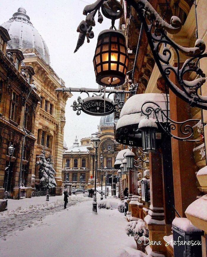 Snow-covered street and vintage lamps in a beautiful place, with historic architecture in the background.