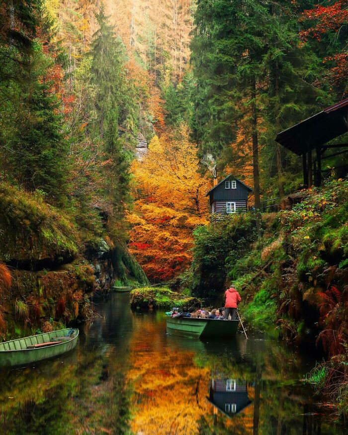 Boat on a serene river with autumnal trees and a rustic cabin, showcasing a beautiful place discovered.