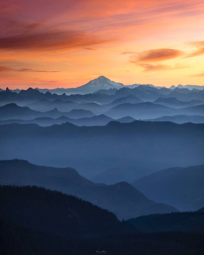 Mountain landscape with layers of blue peaks at sunset, showcasing a beautiful place.
