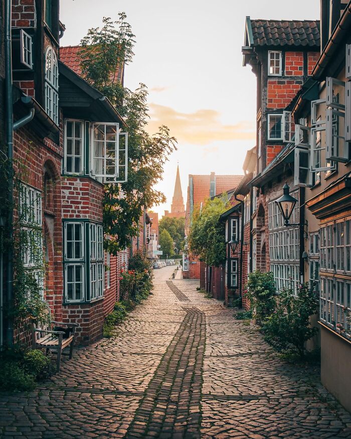 Cobblestone street lined with charming, historic buildings at sunset, showcasing a beautiful place discovered.