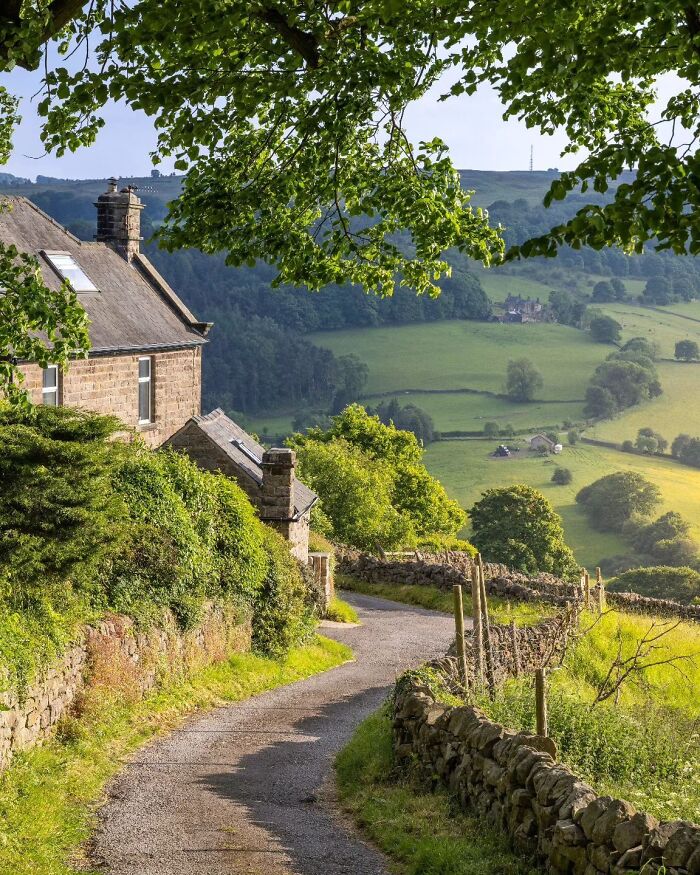 Stone cottage with lush greenery and winding path, showcasing a beautiful place in the countryside.