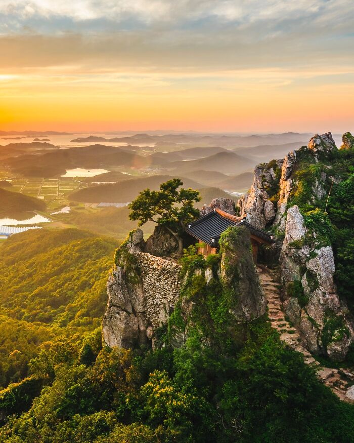 Clifftop temple at sunrise with lush green hills, showcasing one of the most beautiful places discovered.