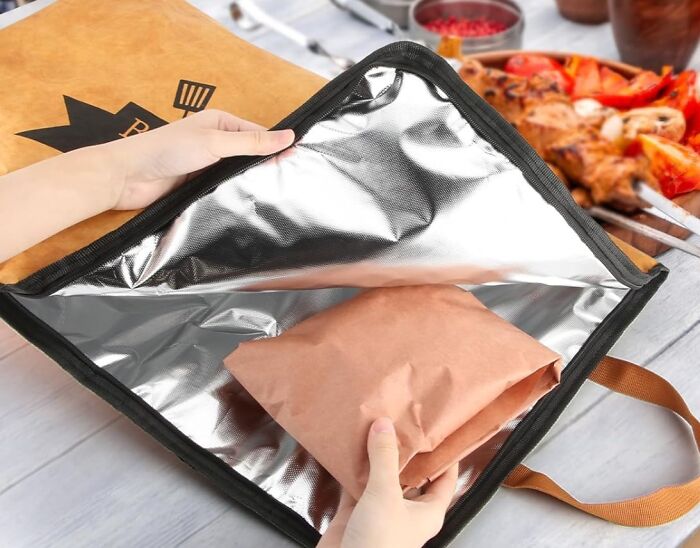 Hands placing a food package inside an insulated bag, highlighting a genius kitchen find for keeping meals warm.