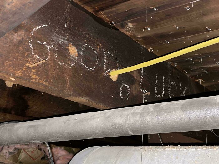 Creepy discovery of "Good Luck" carved into wooden beam in dimly lit home basement.