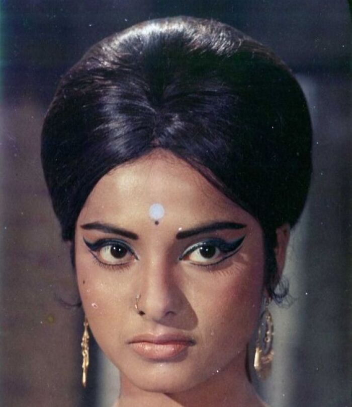 Retro hairstyle with dramatic eye makeup and traditional jewelry.