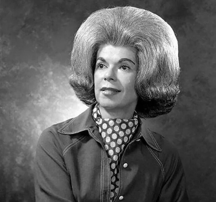 Vintage photo showcasing an absurd and amazing hairstyle from the past, with voluminous hair and a polka dot scarf.