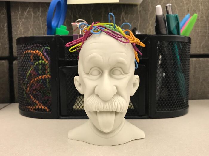 Bust sculpture with colorful paper clips, enhancing work supplies on a desk.