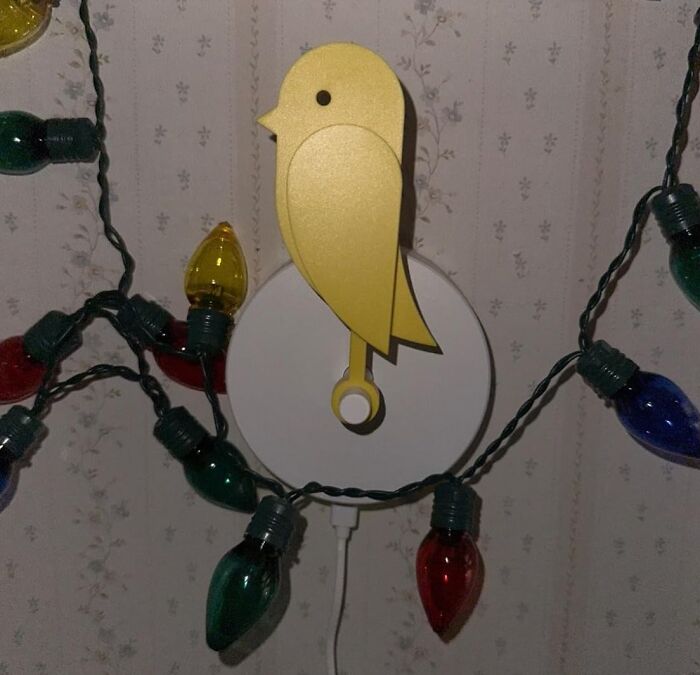 Yellow bird wall hook with colorful string lights, work supplies decor.