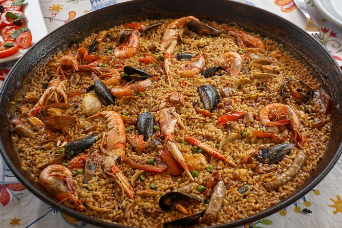 Seafood paella in a large pan, showcasing Spain's top dish with shrimp, mussels, and rice.