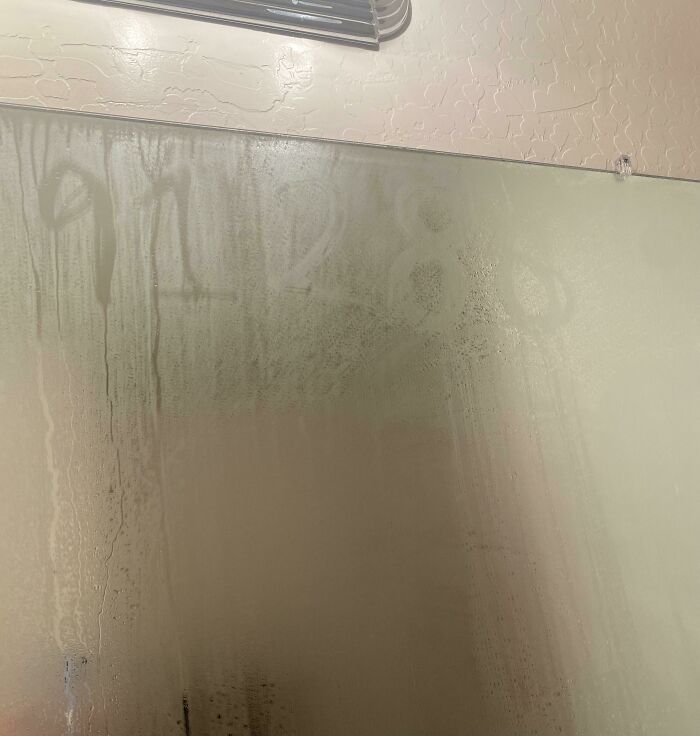 Mysterious numbers appear written on a foggy bathroom mirror, discovered after moving into a new home.