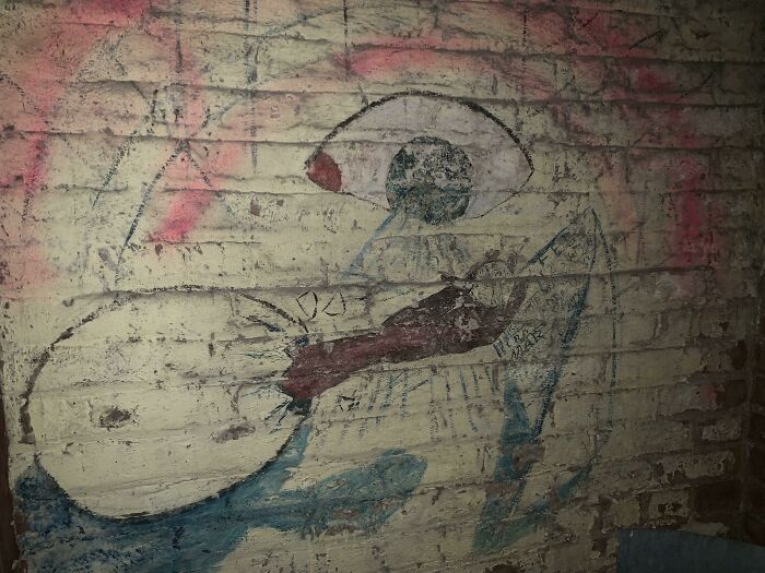 Creepy eye mural on a brick wall, found hidden in a home.