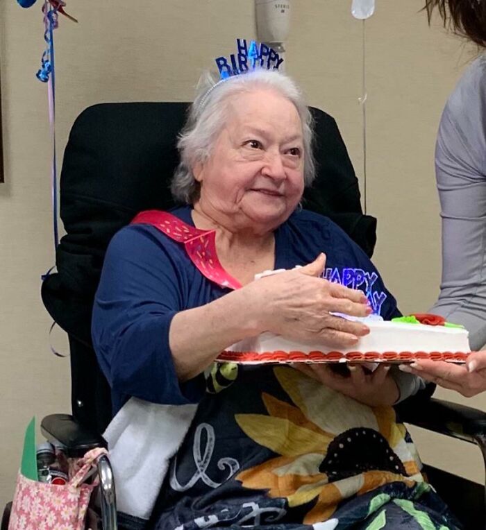 Elderly woman joyfully holding a birthday cake, showcasing her fun spirit.