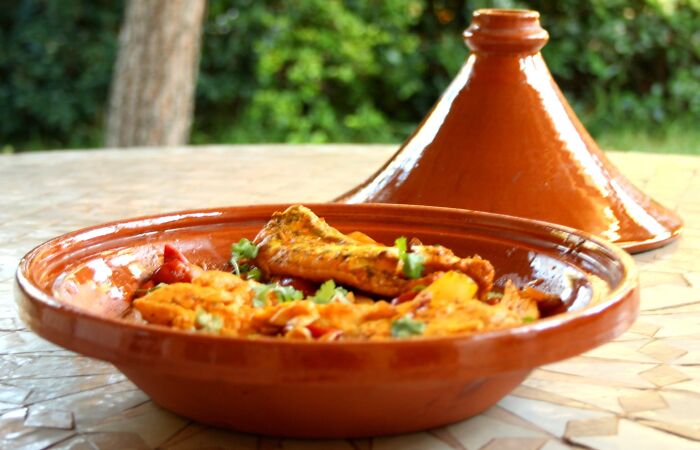 Traditional Moroccan dish in a tagine on a tiled table outdoors, highlighting different countries' top dish.