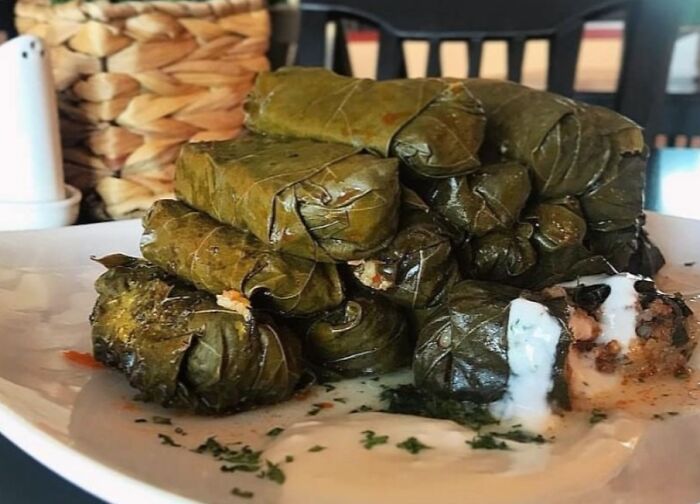 Stuffed grape leaves on a white plate, showcasing a top dish from different countries.