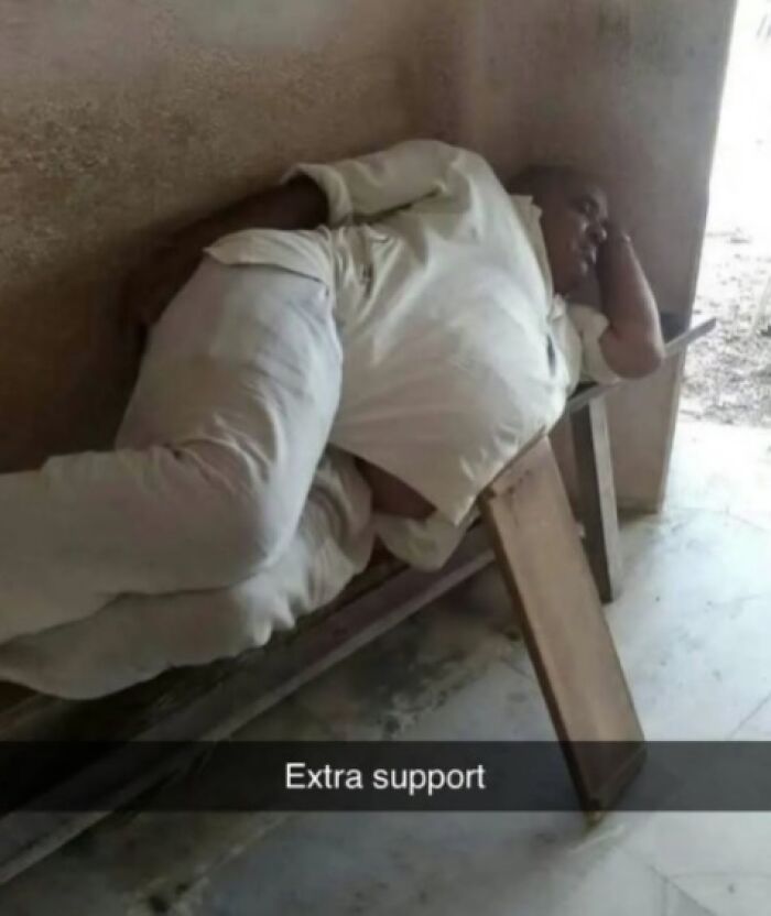 A person lying on a narrow bench with extra support under it, adding a funny twist to a random situation.