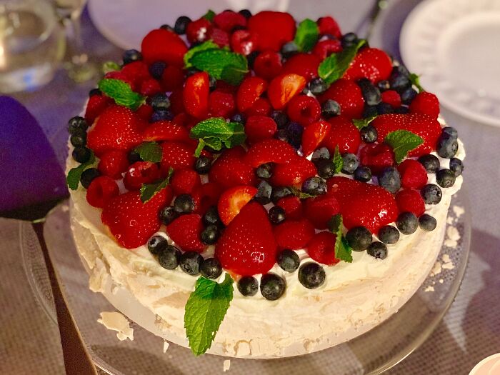 A pavlova topped with fresh berries and mint, showcasing a top dish from different countries.