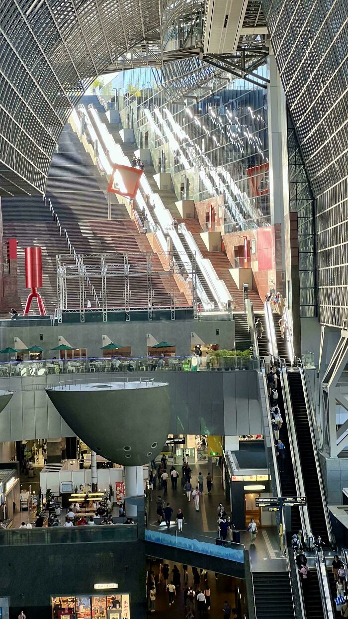 Complex architectural scene with escalators and mirrored surfaces creating an illusion of fake perspectives.