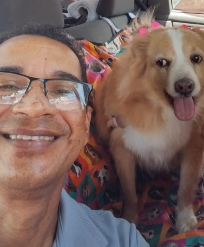Smiling man takes a selfie with a happy dog in his pet taxi, showcasing the friendly atmosphere of his pet taxi business.