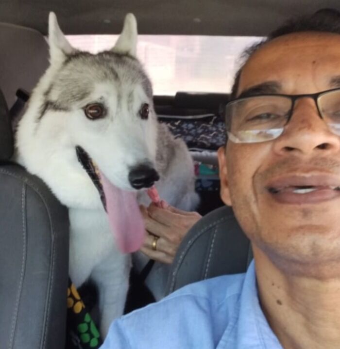 Man in glasses taking a selfie with a happy husky in his pet taxi business.