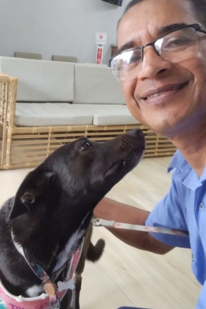 Man in glasses and blue shirt smiling with a dog in a pet taxi business selfie.