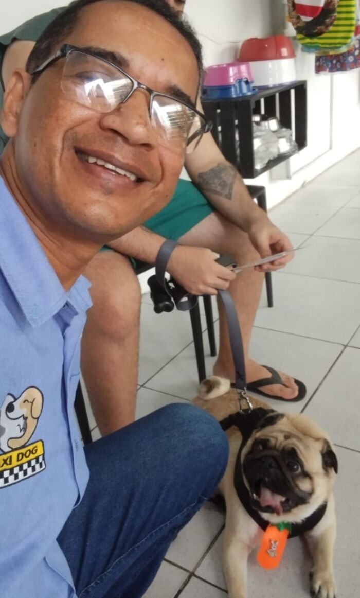 Man in blue shirt taking a selfie with a happy pug, showcasing pet taxi business moments.