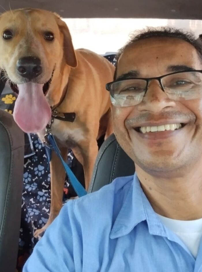 Man in glasses taking a selfie with a happy dog in his pet taxi service.