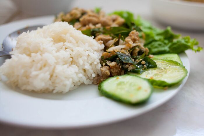 Rice and stir-fried dish with cucumbers and greens on a white plate, representing a top dish from different countries.