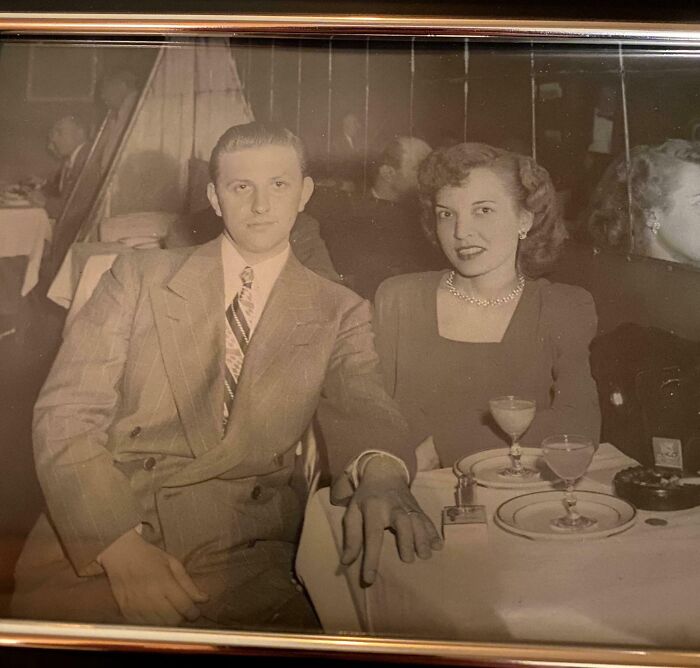 Vintage photo of a couple in formal attire at a restaurant, capturing a fascinating old moment from history.