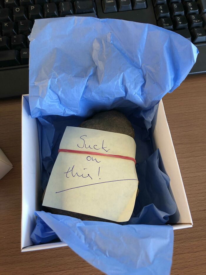 Rock in a gift box with a humorous note, showcasing funny coworkers and their humor at the office.