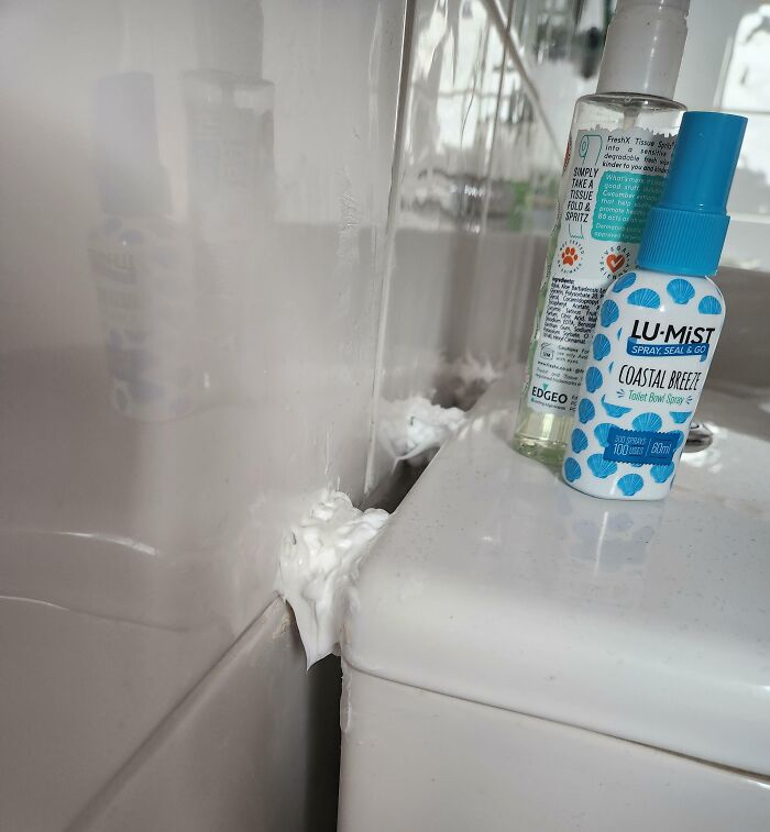 Failed bathroom repair with excessive foam sealant and toiletries on the side.