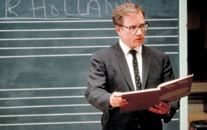A person holding a book in front of a chalkboard, evoking emotional scenes from tear-inducing movies.