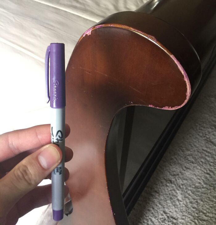 Failed repair attempt using a purple marker on wood furniture damage.