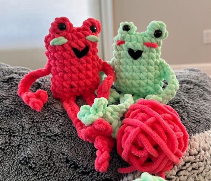 Two colorful crocheted frogs sitting on a blanket with bright yarn, perfect for those who dream in color.