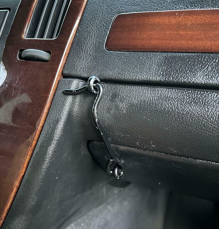 Failed repair attempt using a hook to fix a car compartment.