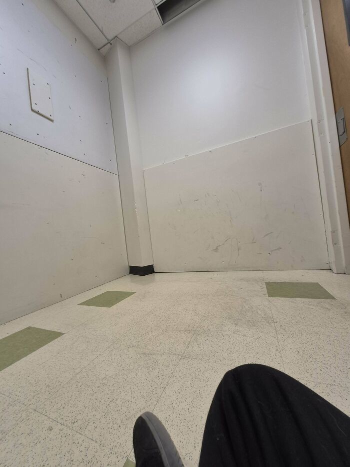 Plain corner of a room with scuff marks and a person seated, reflecting frustration online.