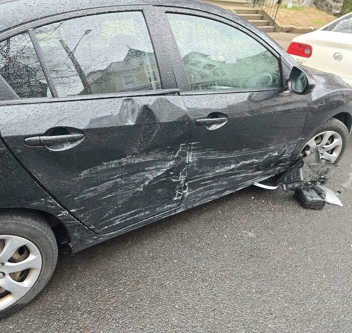 Damaged black car with side dents and scratches, highlighting a moment of frustration shared online.